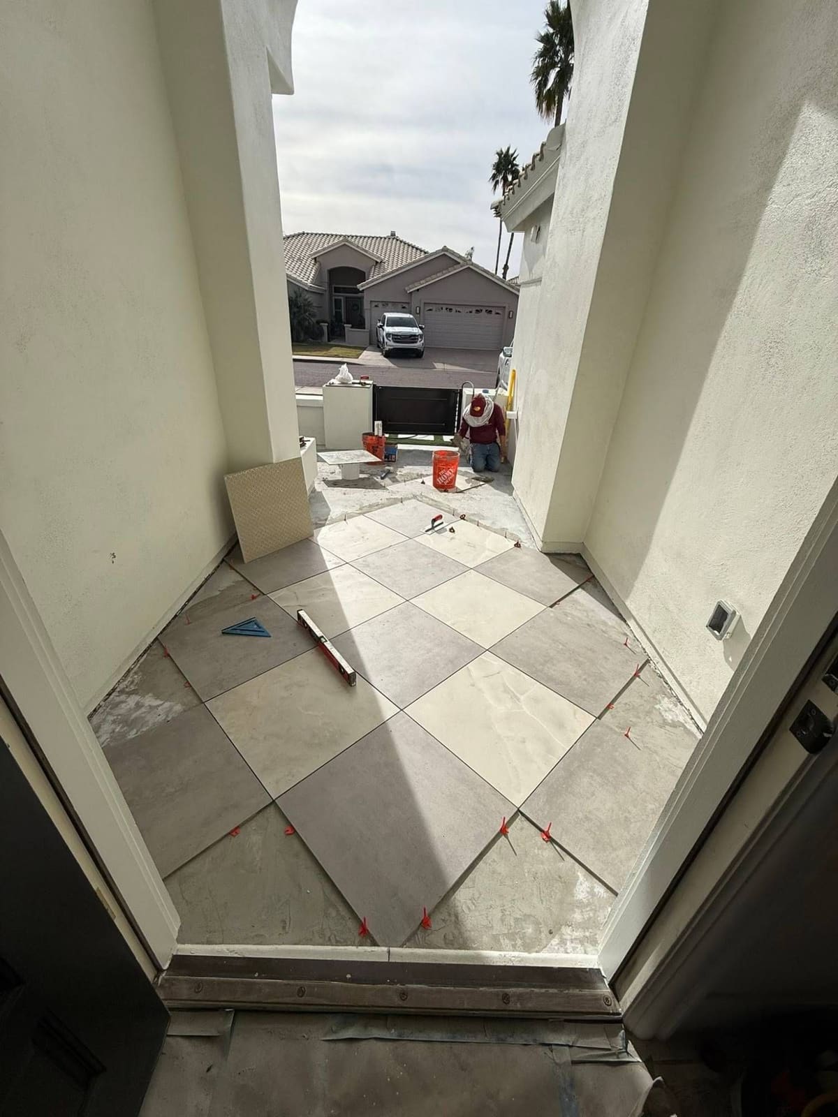 Large-format tile laid on the diagonal in a front entry, with leveling clips in place