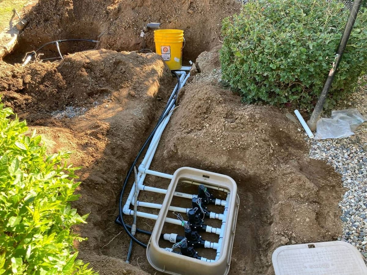 Irrigation valve manifold with new PVC lines set in an open trench
